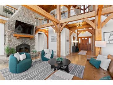 Inviting living room showcasing a stone fireplace, wood beams, and comfortable seating arrangements at 13326 Kuehster Rd, Littleton, CO 80127