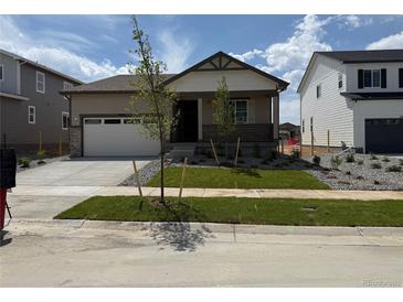 Charming single-story home featuring a manicured lawn, covered porch, and a two-car garage at 2668 Simpson Ln, Erie, CO 80026
