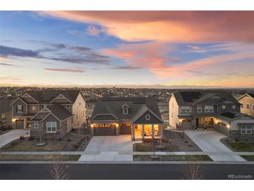 Charming single-Gathering home featuring solar panels, a two-car garage and covered front porch at dusk at 8751 S Wenatchee Ct, Aurora, CO 80016