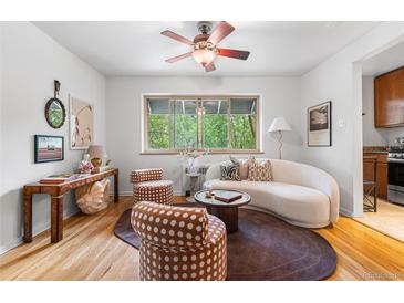 Bright living room features a ceiling fan, hardwood floors, modern furnishings, and a large window with tree views at 2100 N Franklin St # 5, Denver, CO 80205