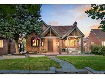 Charming brick home featuring a covered front porch, manicured lawn and beautiful landscaping at 1418 Glencoe St, Denver, CO 80220