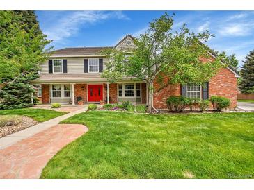 Charming two-story home boasts a beautiful front yard, brick accents, and a welcoming red front door at 1583 Sunset Ridge Rd, Highlands Ranch, CO 80126