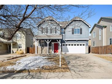 Charming two-story home with a red front door, stone accents, and a two-car garage at 14441 E 102Nd Ave, Commerce City, CO 80022