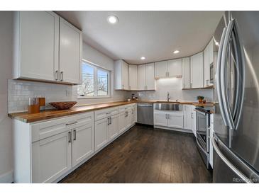Bright kitchen featuring white cabinets, subway tile backsplash, butcher block counters and stainless steel appliances at 6026 Iris Way, Arvada, CO 80004