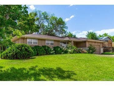 Charming single-story home with a well-manicured lawn, mature trees, and blossoming flower beds at 6131 Wolff St, Arvada, CO 80003