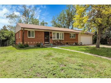Inviting single-story brick home with a lush green lawn, mature tree, and attached garage at 8660 De Soto St, Denver, CO 80229