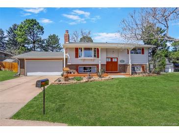 Charming home with mature trees, green lawn, colorful flower beds, and a cozy front porch at 3785 S Benton Way, Denver, CO 80235