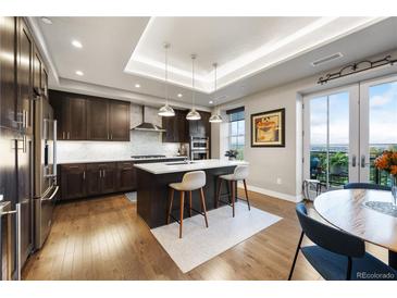 Modern kitchen boasts dark wood cabinetry, white countertops, stainless steel appliances, and a central island with bar seating at 4625 W 50Th Ave # 309, Denver, CO 80212