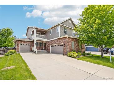 Beautiful two-story home featuring brick and siding, a three-car garage, and covered porch with a well-manicured lawn at 17020 E 107Th Ave, Commerce City, CO 80022