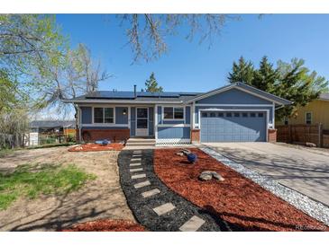 Charming blue home featuring a two-car garage, solar panels, and a beautifully landscaped front yard at 16933 E Bethany Pl, Aurora, CO 80013