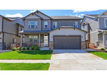 Charming two-story home with a well-manicured lawn and a two-car garage at 9835 Uravan St, Commerce City, CO 80022