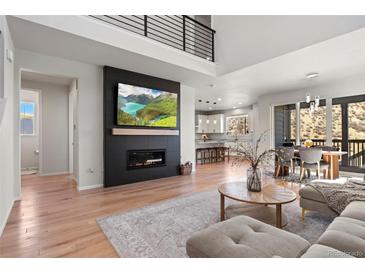 Bright, open-concept living room with a modern fireplace, wood floors, and access to the dining area and kitchen at 1044 Oleander St, Castle Rock, CO 80109