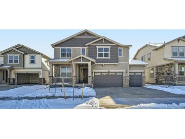 Two-story house with gray siding, a double-car garage, and a snowy front yard at 4620 Thistle Dr, Brighton, CO 80601