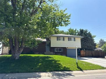 Charming two-story home with brick accents, green lawn, mature shade tree, and freshly painted trim at 1492 S Dudley St, Lakewood, CO 80232