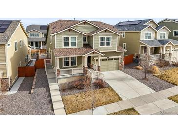 Charming two-story home with green siding, a covered porch, well-maintained landscaping, and an attached garage at 14881 Chicago St, Parker, CO 80134
