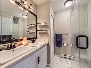 Modern bathroom featuring double sinks, a large mirror, and a glass-enclosed shower, with sleek fixtures and finishes at 2280 S Oswego Way # 104, Aurora, CO 80014