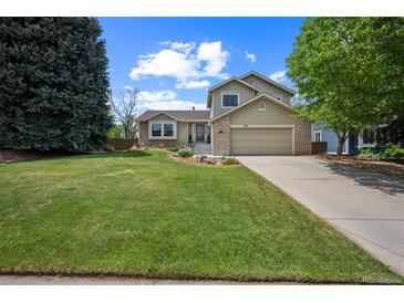 Charming two-story home featuring a lush green lawn, mature trees and an attached two-car garage at 9361 Crestmore Way, Littleton, CO 80126