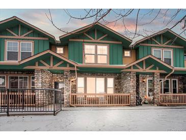 Inviting townhomes featuring green siding, stone accents, and charming front porches in a snow-covered setting at 643 S Norfolk Way, Aurora, CO 80017