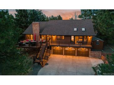 Beautiful brown two-story home featuring large deck, outdoor seating and three-car garage with well-lit driveway at 8140 Lightening View Dr, Parker, CO 80134