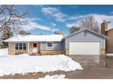 Charming single-story home featuring brick accents, an attached two-car garage and a well-maintained front lawn during winter at 1606 S Flanders Way, Aurora, CO 80017