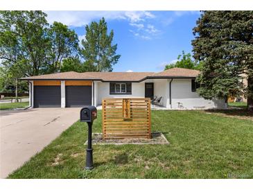 Charming ranch-style home with a well-manicured lawn, two-car garage, and decorative front yard accents at 9197 W Woodard Dr, Lakewood, CO 80227