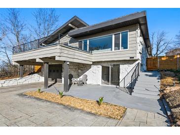 Unique home featuring stone accents, a balcony, two-car garage, and manicured landscaping adding to its curb appeal at 5390 Rosemary Ln, Denver, CO 80221
