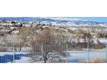 Scenic view of snow-covered mountains and neighborhood in the distance with a fenced foreground at 8627 Gold Peak Pl # C, Highlands Ranch, CO 80130