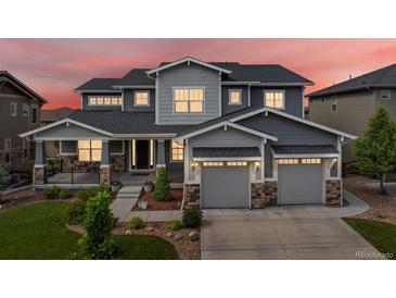 Beautiful two-story home with a manicured lawn, stone accents, and a three-car garage under a colorful dusk sky at 22263 Boundstone St, Parker, CO 80138