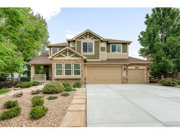 Charming two-story home with three-car garage, stone accents, and beautifully landscaped front yard at 15348 W 75Th Pl, Arvada, CO 80007