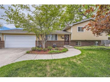 Charming home featuring a manicured front yard, brick accents, and a welcoming walkway to the front door at 164 W Acoma Dr, Littleton, CO 80120