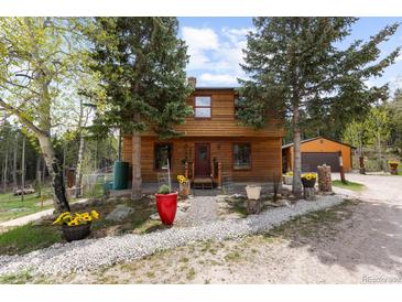 Charming cabin with wood siding and a well-manicured front yard and front yard landscaping at 8600 S Warhawk Rd, Conifer, CO 80433