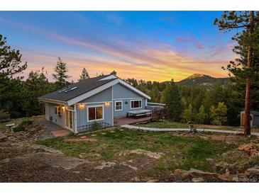 Inviting two-story home featuring a charming deck and picturesque mountain views at sunset at 11348 Ranch Elsie Rd, Golden, CO 80403