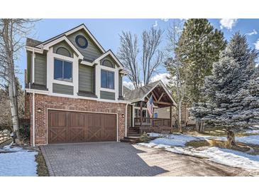 Charming two-story home with a brick and wood exterior, complemented by a paved driveway and a covered front porch at 27 Buckthorn Dr, Littleton, CO 80127