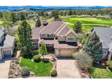 Beautiful two-story home with stone accents, manicured lawn, mature trees and mountain view at 7083 Turweston Ln, Castle Pines, CO 80108