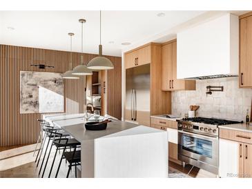 Modern kitchen with stainless steel appliances, wood cabinets, large island and hardwood floors at 2471 Quitman St, Denver, CO 80212