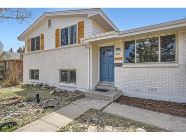 Charming two-story home with white brick, wood shutters, a blue door, and a well-maintained front yard at 709 S Alkire St, Lakewood, CO 80228