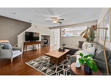 Inviting living room with hardwood floors, a stylish rug, comfortable seating, and a ceiling fan at 7887 S Kittredge Cir, Englewood, CO 80112