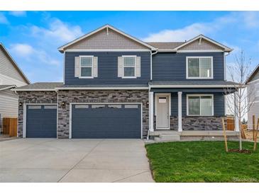 Charming two-story home featuring a three-car garage, stone accents and a well-manicured lawn at 13477 Valentia St, Thornton, CO 80602