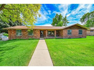 Charming one-story brick home featuring a well-manicured lawn and a concrete walkway to the front door at 2311 Emery Pl, Longmont, CO 80501