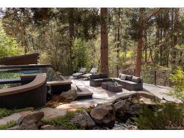 Beautiful backyard setting, featuring a pool, water feature and outdoor seating area amidst mature trees at 1070 Cypress Way, Castle Rock, CO 80108