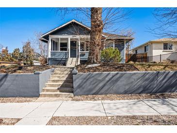 Charming blue two-story home featuring a well-maintained yard with landscaped front and concrete stairs at 5094 Meade St, Denver, CO 80221