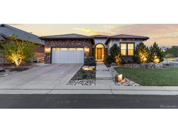 Beautiful single-story home with a two-car garage, stone accents, and manicured landscaping at 10660 Winding Pine Pt, Highlands Ranch, CO 80126