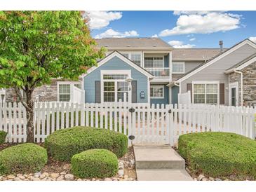 Charming townhome featuring a white picket fence, lush landscaping, and a welcoming entryway at 11386 Grove St # B, Westminster, CO 80031