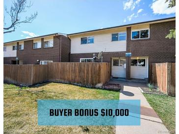 A charming townhouse with a brick facade, a well-maintained lawn, and a wooden fence at 8019 Wolff # G, Westminster, CO 80031