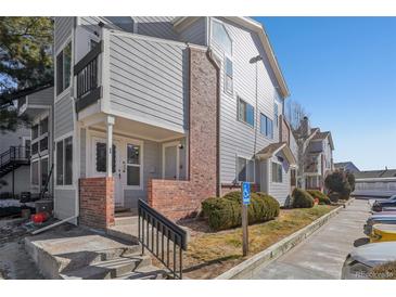 Attractive townhome featuring gray siding, brick accents, and convenient accessible parking in a well-maintained complex at 5550 W 80Th Pl # 1, Arvada, CO 80003