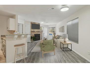 Bright living room with stone fireplace and TV, seamlessly connecting with the kitchen counter seating at 5550 W 80Th Pl # 1, Arvada, CO 80003