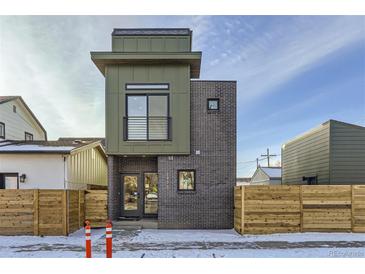 Modern home showcasing a brick exterior with a unique architectural design and a charming fenced yard at 1928 W 41St Ave, Denver, CO 80211