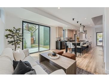 Bright and airy living room featuring hardwood floors and a seamless flow to the modern kitchen and backyard access at 1928 W 41St Ave, Denver, CO 80211