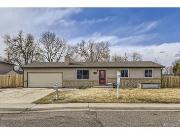 Charming ranch-style home with tan siding, red door, and well-maintained front yard at 11964 W 71St Pl, Arvada, CO 80004