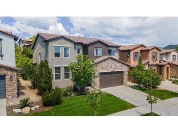 Charming two-story home featuring a stone garage facade and a well-maintained lawn, offering curb appeal at 2347 S Loveland St, Lakewood, CO 80228